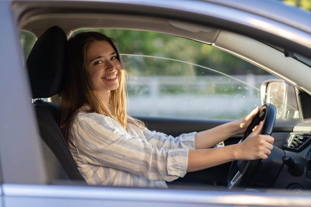 Mujer migrante en el asiento de su auto conduciendo con una licencia de conducir para migrantes