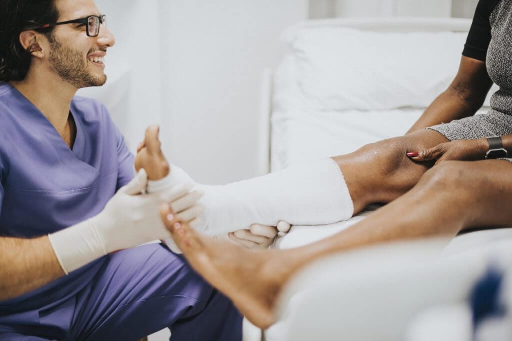 Médico atendiendo la fractura de pie de su paciente