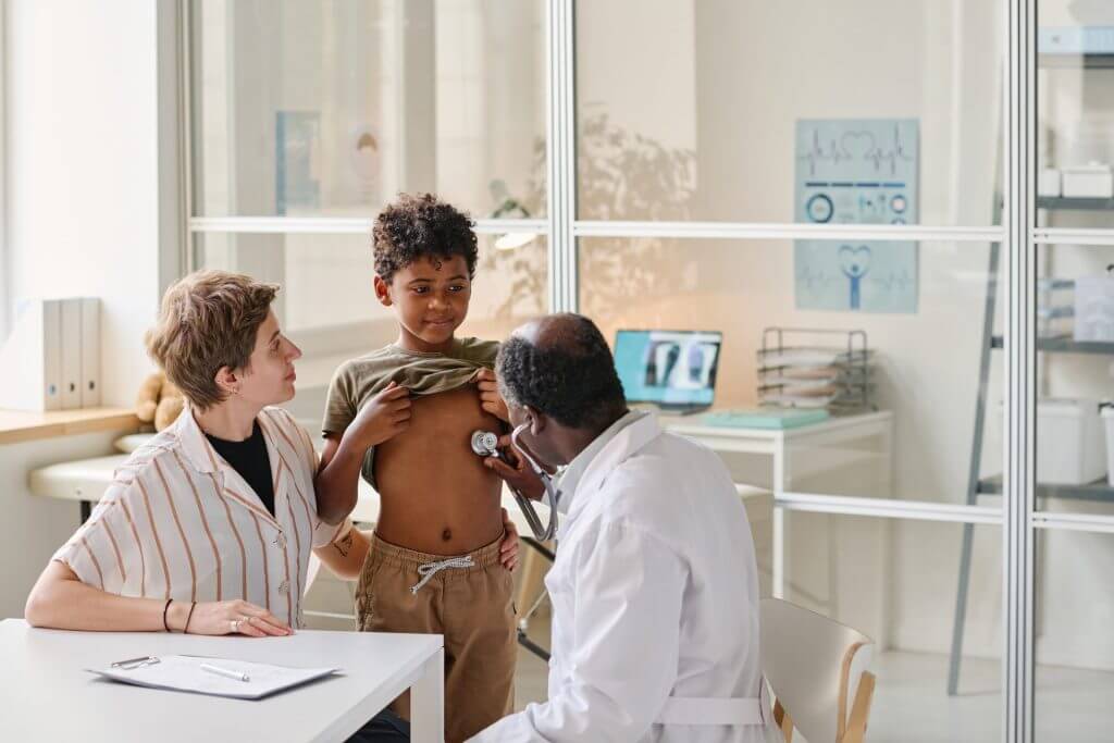 Pediatra atendiendo a un niño mientras le explica el tratamiento a su padre