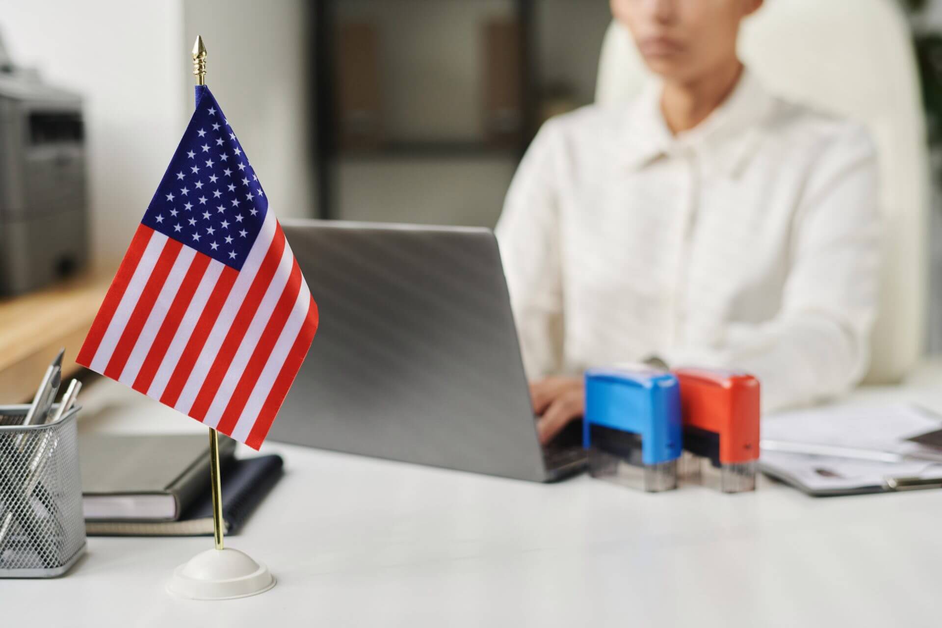 Trabajador las oficinas de USCIS sentado en su despacho frente a una bandera de USA