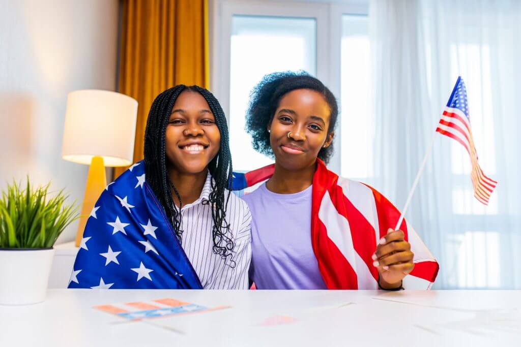 Dos chicas envueltas en la bandera de USA celebrando su ciudadanía