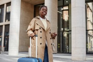 Mujer migrante con documento de viaje para residentes permanentes y valija en mano