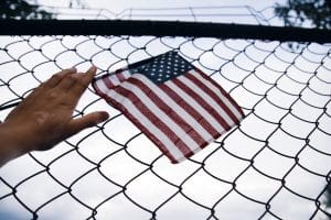 Mano con una bandera de USA sobre una reja representando la amnistía en Estados Unidos