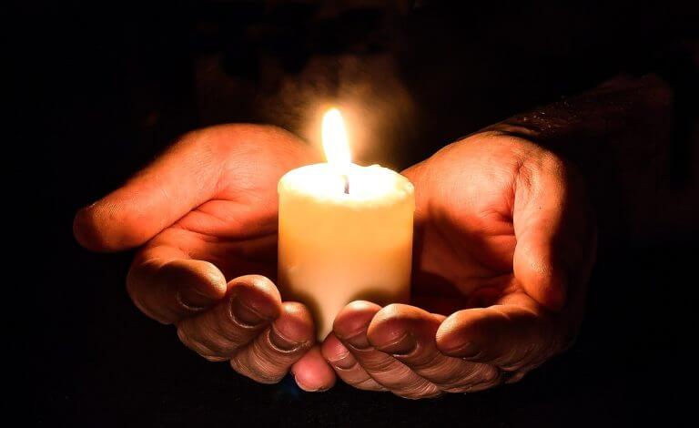 Manos sosteniendo una vela representando las iglesias en Estados Unidos que ayudan a migrantes