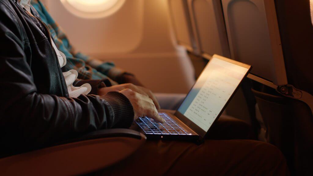 Viajero en avión revisando su laptop