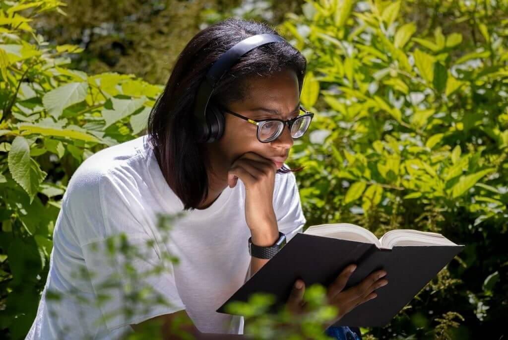 Estudiante leyendo un libro con concentración en un parque