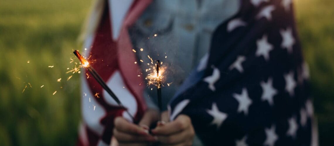 Niña con bandera de Estados Unidos y estrellitas en la mano, celebrando el Dia de la Independencia USA