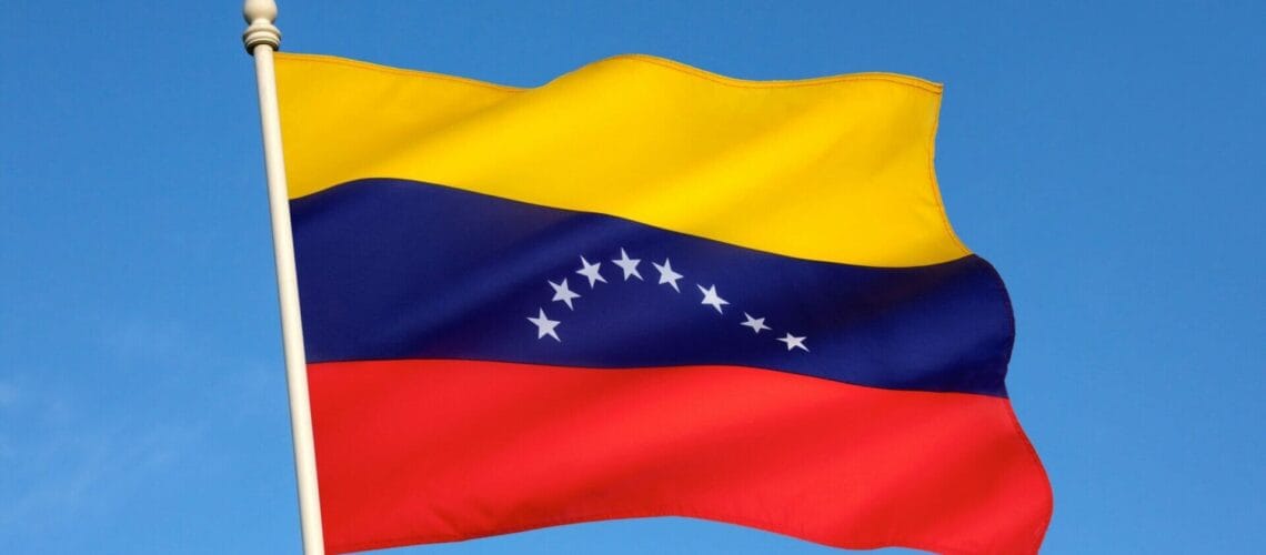Bandera de Venezuela ondeando sobre el cielo azul.