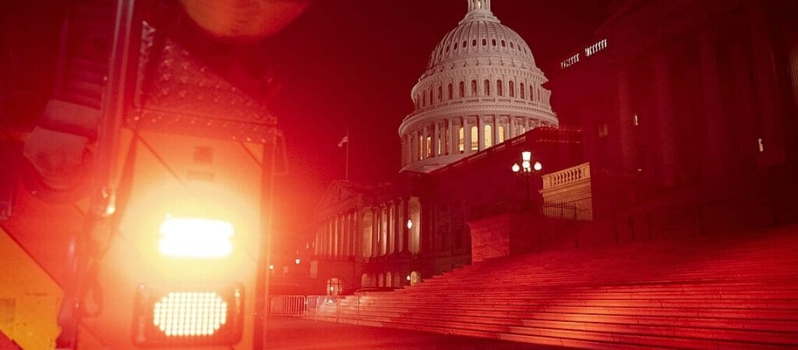 Este artículo habla sobre la teoría conspirativa del Gran Reemplazo. La imagen muestra al Capitolio de los Estados Unidos iluminado con luz roja de un vehículo en la noche del 6 de Enero de 2021.