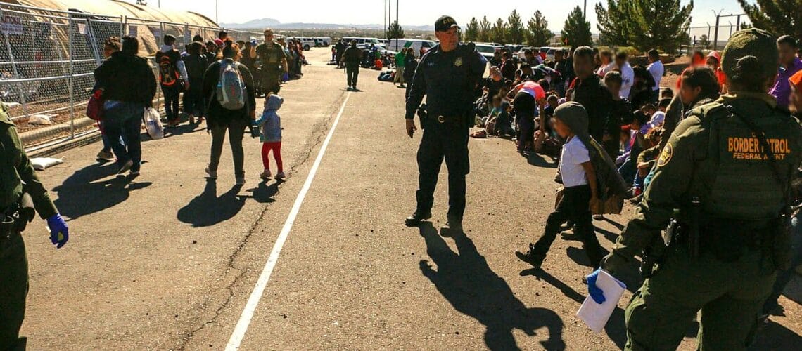 Este artículo habla sobre la posible declaración de emergencia en la frontera en El Paso, Texas. La imagen muestra una caravana detenida por oficiales de la ley.