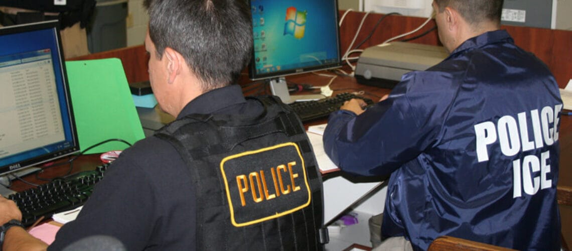 Oficiales de ICE trabajando en computadoras.