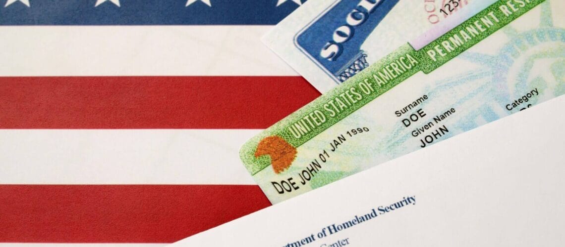 Tarjeta verde, tarjeta de seguro social y documento de migraciones sobre bandera de Estados Unidos.