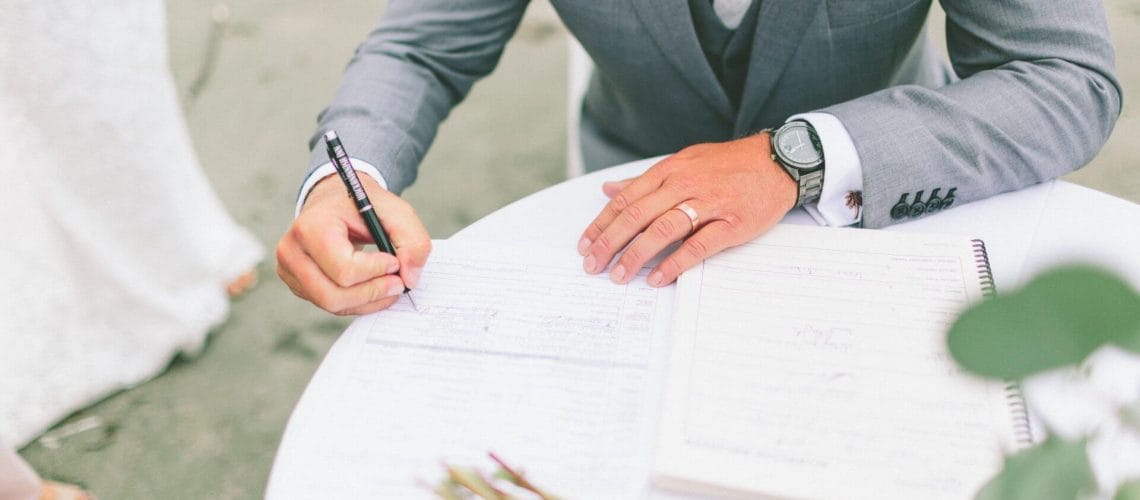 Marido firmando documentos de matrimonio tras averiguar que necesito para casarme en usa