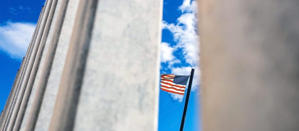 Bandera de los Estados Unidos vista a través del muro fronterizo, simbolizando los centros de procesamiento USCIS de inmigración.