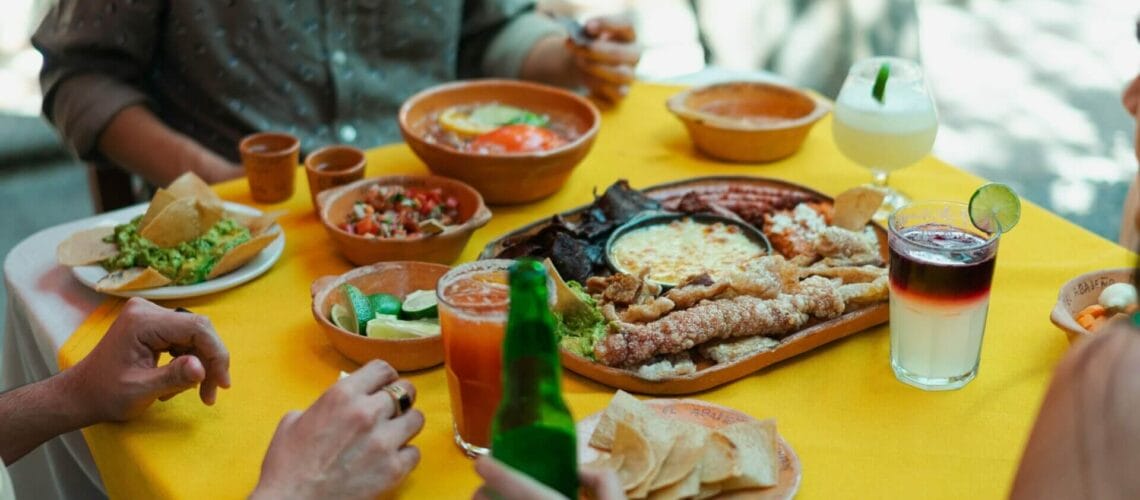 Este artículo habla sobre platos latinos populares en Estados Unidos. La foto muestra una mesa con comida latina donde hay varios comensales.