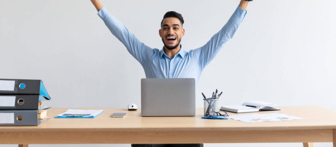 Hombre emocionado frente a su laptop tras enterarse que ganó la loteria de visas 2024