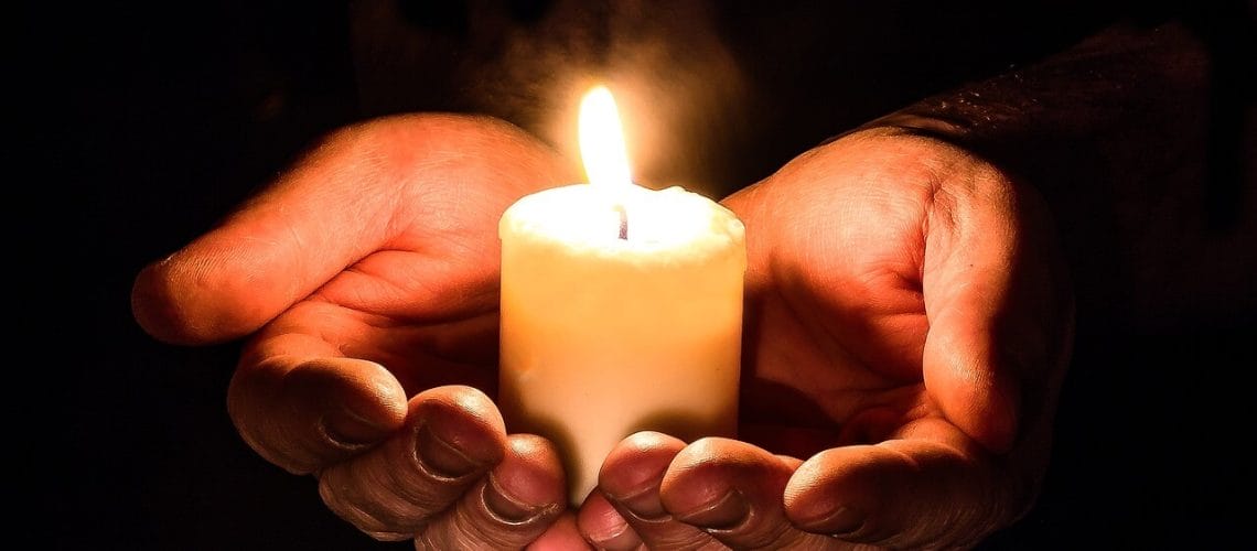 Manos sosteniendo una vela representando las iglesias en Estados Unidos que ayudan a migrantes