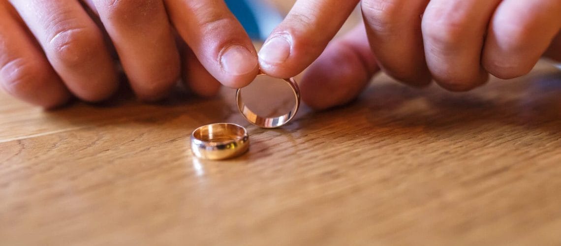 Manos del novio con anillos de compromiso en la mesa tras investigar si dos inmigrantes se pueden casar en estados unidos