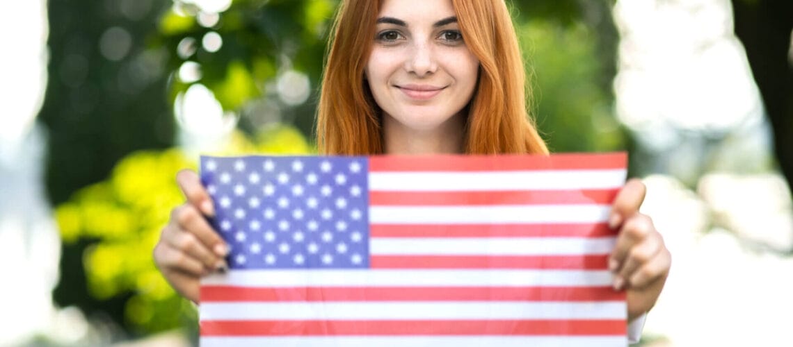 Mujer sosteniendo una bandera de USA celebrando su nuevo estado migratorio legal