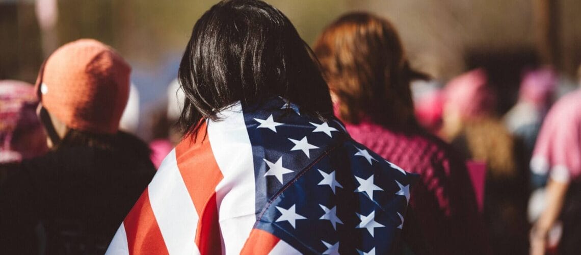Mujer carga en sus hombros una bandera de los estados unidos