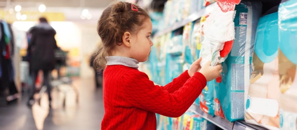 Niña pequeña en el supermercado viendo pañales gracias a las tarjetas de credito para inmigrantes