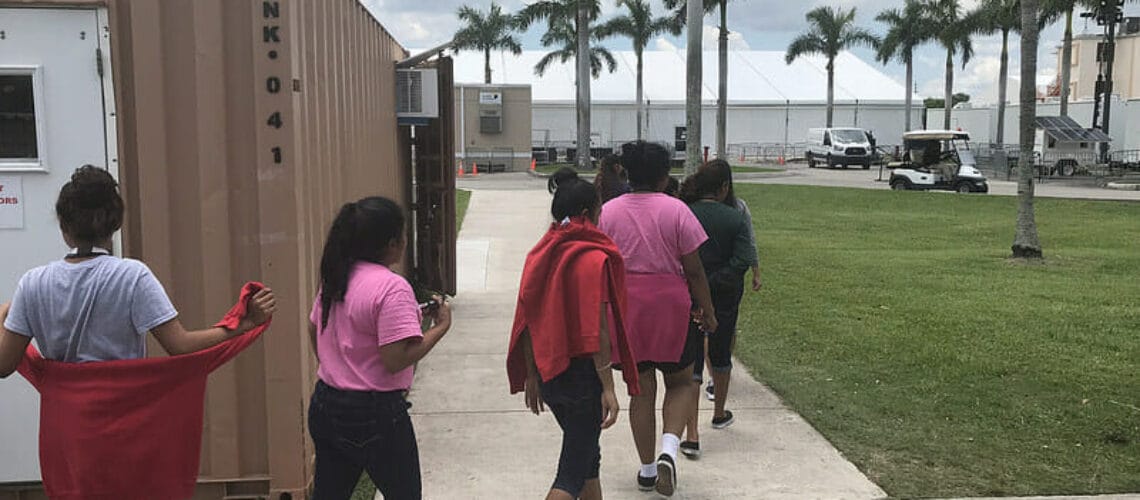 Este artículo habla sobre los migrantes menores no acompañados. La imagen muestra un grupo de chicas migrantes menores en un refugio en Florida.