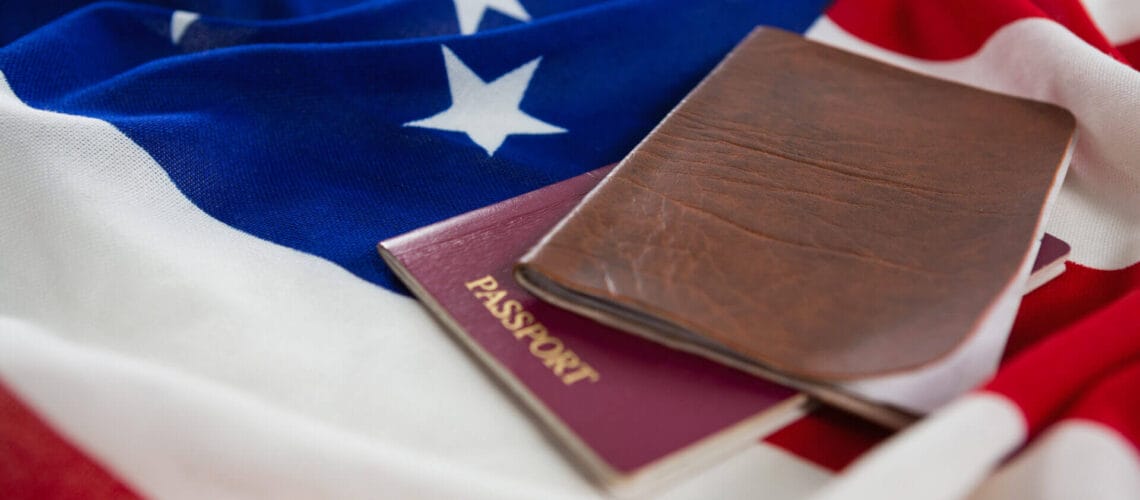 Imagen de bandera estadounidense junto a un pasaporte y a diferentes tipos de visa americana