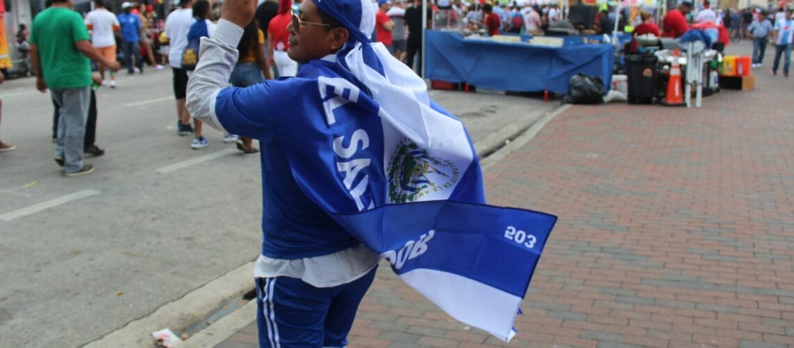 La nota trata sobre la renovación del TPS El Salvador. La imagen muestra a una persona con la bandera de ese país.