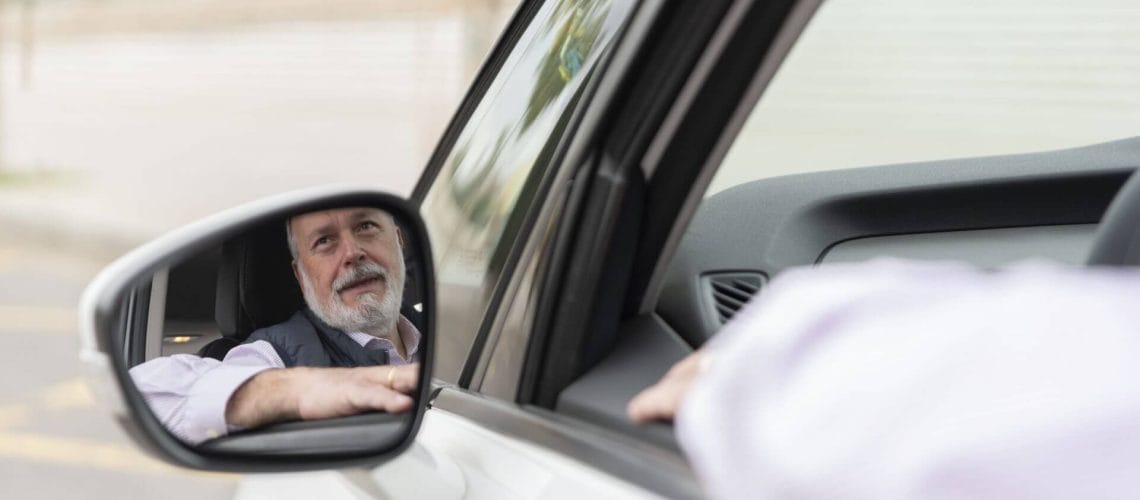 Hombre mayor mirando por el retrovisor de su auto tras obtener una licencia de conducir para indocumentados en pensilvania