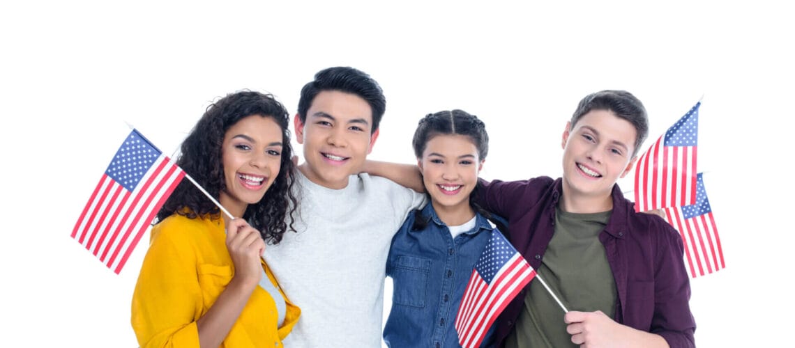 Grupo de estudiantes de intercambio sonriendo con la bandera de USA luego de averiguar cómo puedo cambiar mi estatus de turista a estudiante en USA