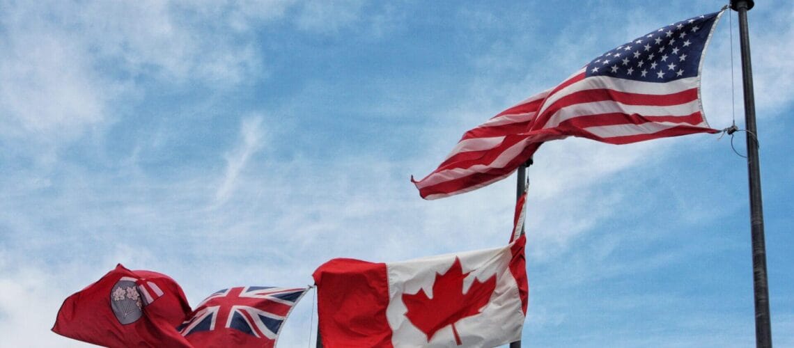 Tres banderas flameando en la frontera de Estados Unidos y Canada